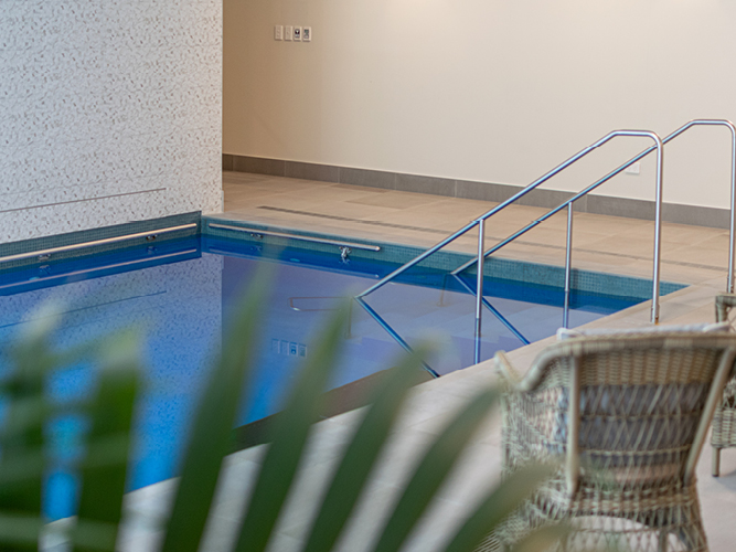 Indoor swimming pool, with a wicker chair and a fern, at Rawhiti Retirement Village.