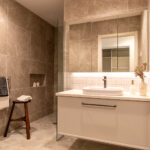 Modern bathroom at Rawhiti Estate retirement village with elegant tiles, glass shower, and a vanity unit with a large mirror.