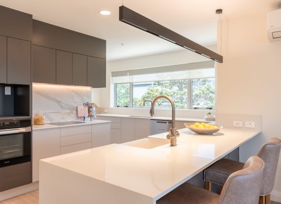 Modern kitchen at Rawhiti Estate retirement village with sleek cabinetry, large island, and seating.